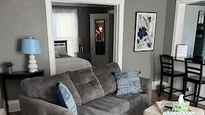 Una sala moderna con un sofá modular, un pequeño reposapiés y un comedor.