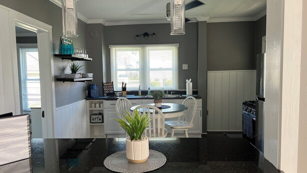 Una cocina moderna con una isla central, armarios blancos y encimera negra.