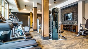 Ett gym med löpband, en styrketräningsmaskin och en tv-skärm på väggen.