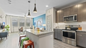 A modern kitchen with stainless steel appliances, a granite countertop, and a central island with stools. - Serene 1BR King Suite Close to Downtown w Fast Wifi (Austin)