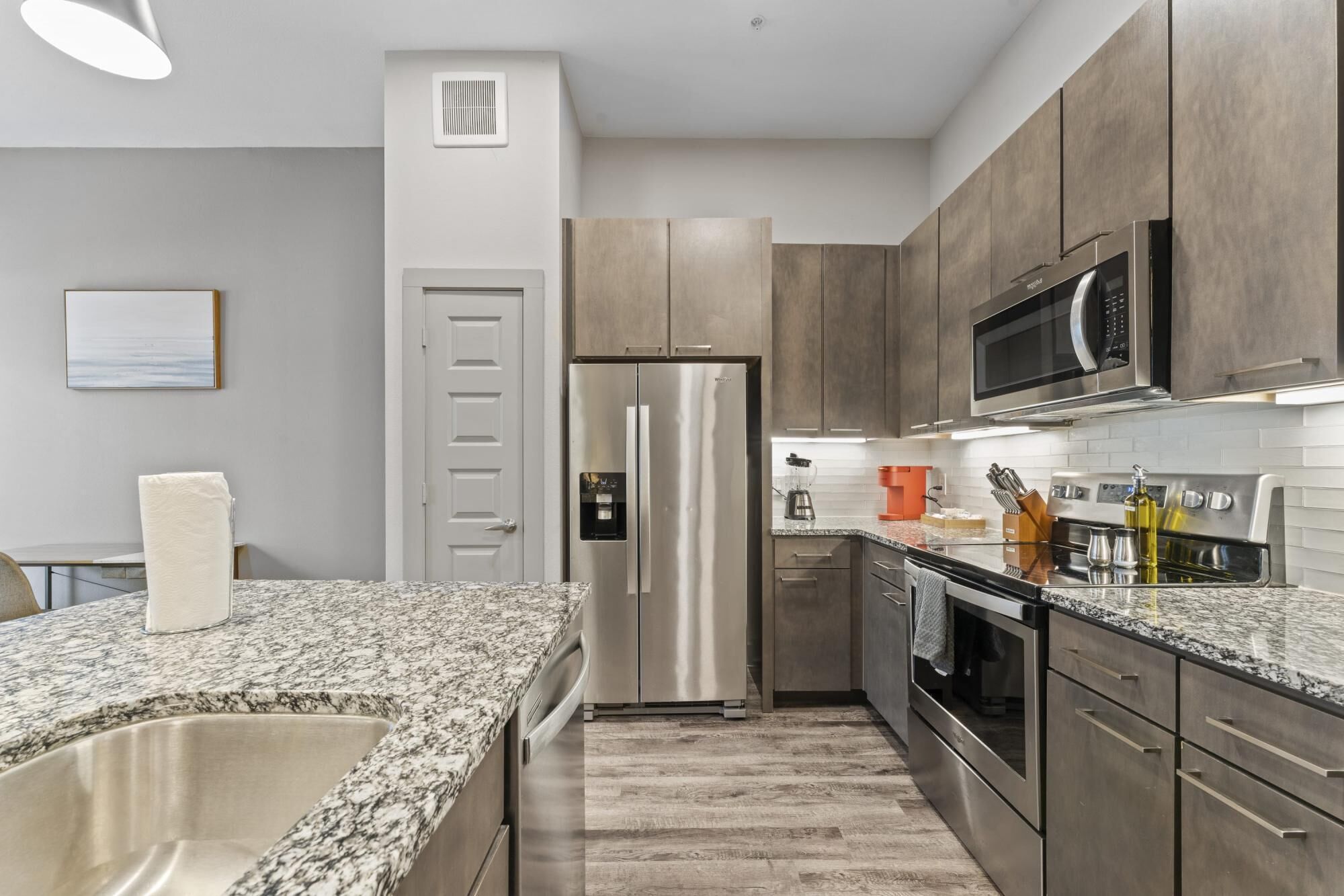 A modern kitchen with stainless steel appliances, granite countertops, and wooden cabinets.