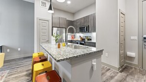 A modern kitchen with granite countertops, stainless steel appliances, and a central island with bar stools.