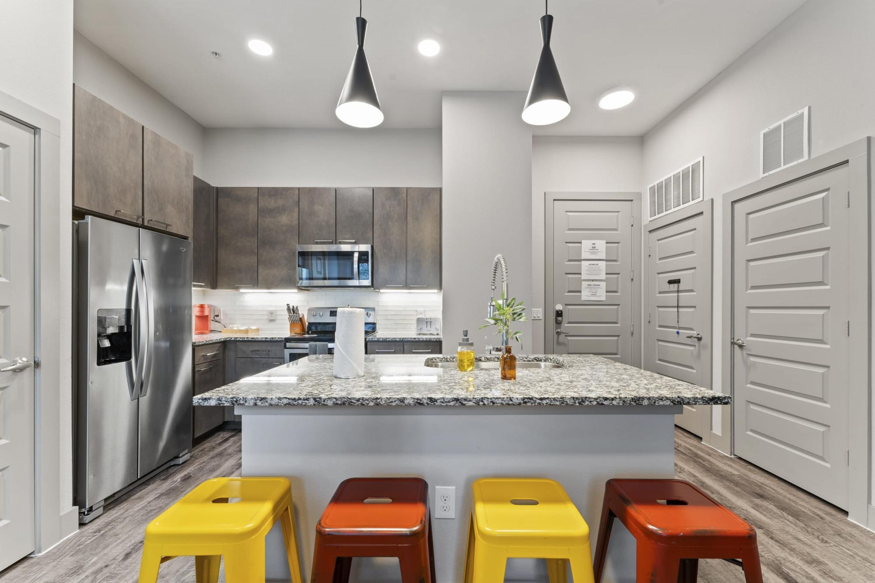 A modern kitchen with a central island, stainless steel appliances, and a microwave.