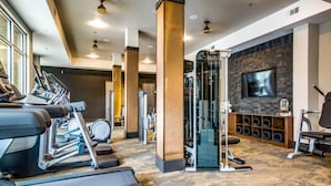 Ett gym med löpband, en styrketräningsmaskin och en tv på väggen.