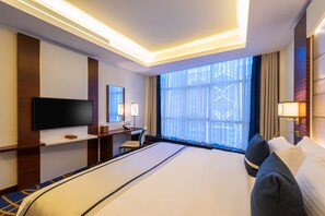 A hotel room with a large bed, a TV, a desk, and a window with curtains. - Blue Diamond Hotel (Jeddah)
