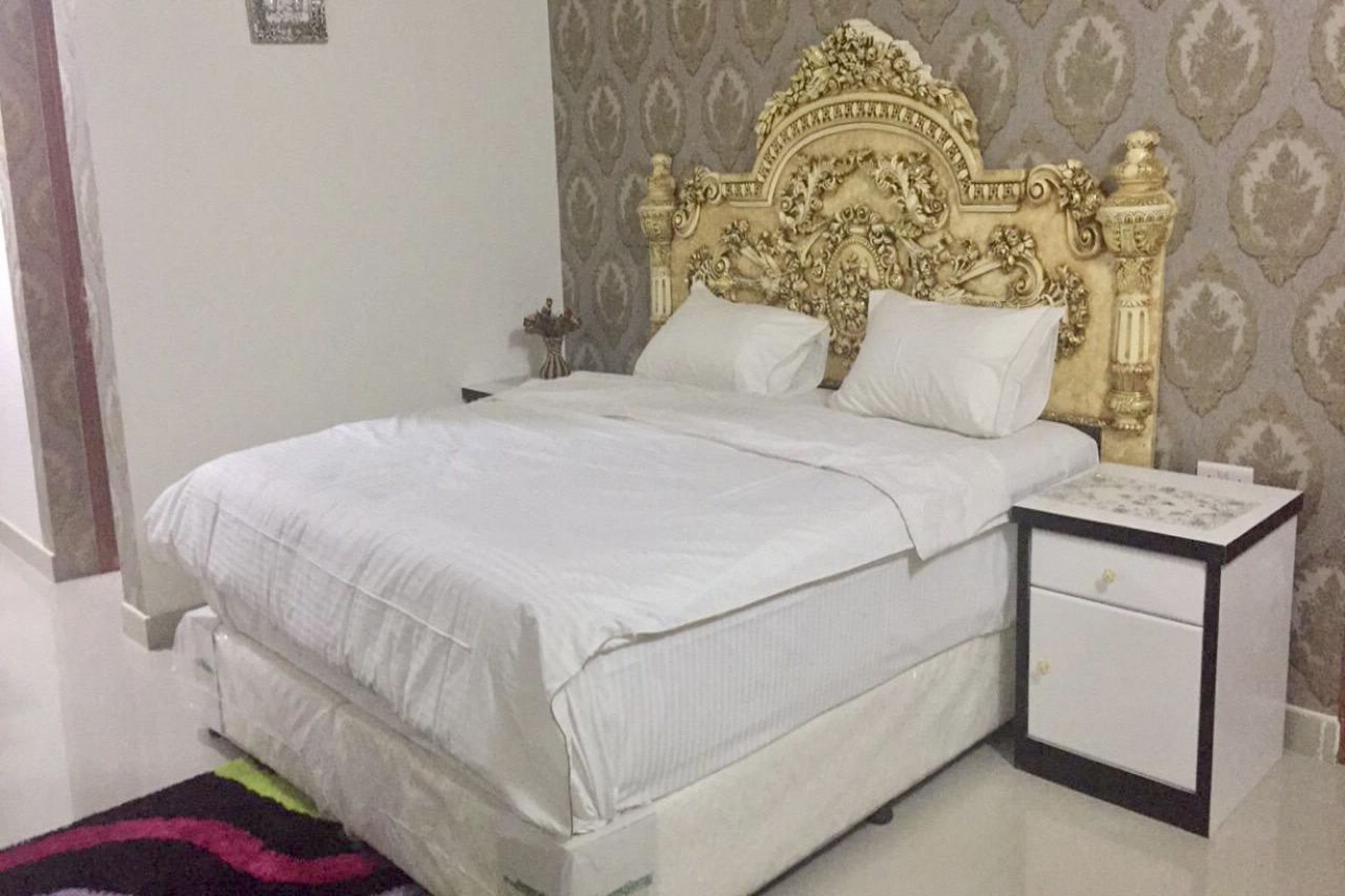 A bed with a white headboard and a nightstand with drawers.