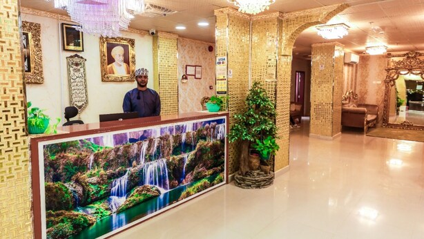 A reception area with a large waterfall mural, a reception desk, and a man standing behind it.