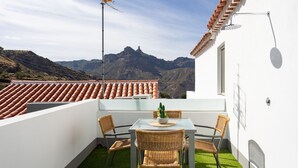 Ein Balkon mit Tisch, Stühlen und einer Topfpflanze.