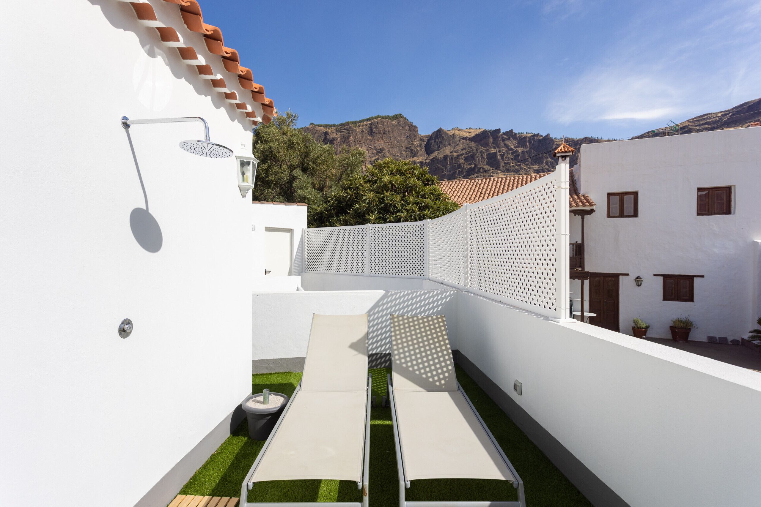 Une terrasse extérieure moderne avec une piscine, un mur blanc et une vue sur les montagnes.
