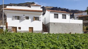 A white building with a stone facade and a red-tiled roof. - Casa Maria with Roque Nublo view (Tejeda)
