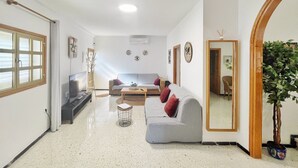 A living room with a sofa, coffee table, TV, and a potted plant. - Casa Maruca with Roque Nublo view (Tejeda)
