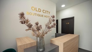 A reception desk with a vase of dried flowers, a wooden counter, and a wall sign that reads "OLD CITY BOUTIQUE HOTEL". - Old City Boutique Hotel (Tbilisi)