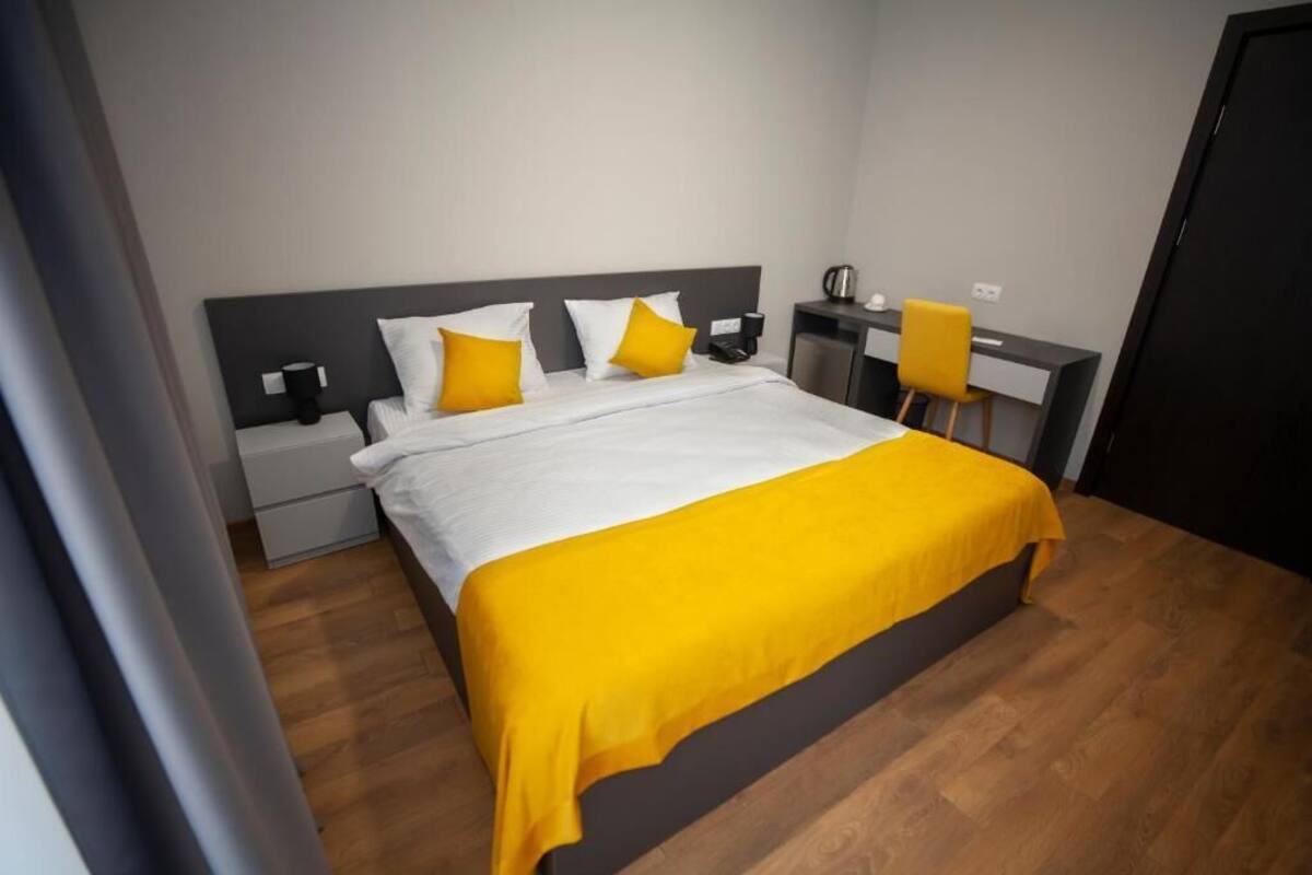 A modern hotel room with a large bed, a desk, and a chair.