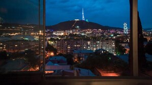 A nighttime cityscape with a prominent hill and a lit tower in the distance. - Old City Boutique Hotel (Tbilisi)