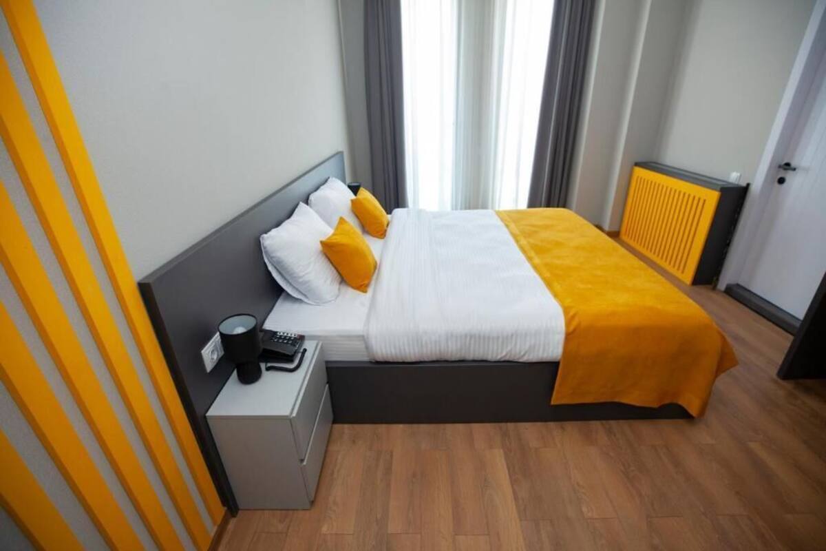 A neatly arranged hotel room with a bed, bedside table, and a radiator.
