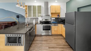 A modern kitchen with a central island, stainless steel appliances, wooden cabinets, and pendant lighting.