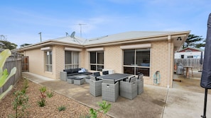 A two-story house with a patio area featuring outdoor furniture and a satellite dish.