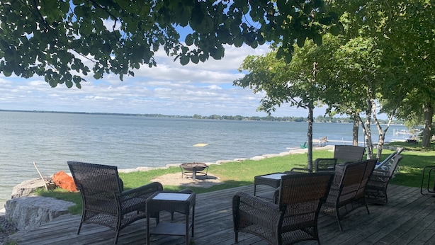 A wooden deck with wicker furniture overlooking a lake.