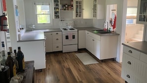 A compact kitchen with white cabinets, a stove, and a sink.