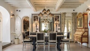 Une salle à manger avec un grand lustre, un buffet en bois et un miroir.