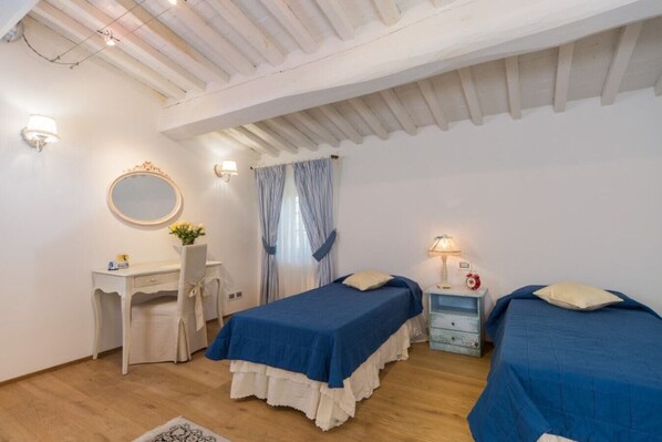 Une chambre avec deux lits, un bureau, une chaise, un miroir et une table de chevet avec une lampe.