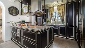 Une cuisine moderne avec des meubles de couleur noire, un îlot central et un luminaire suspendu.