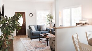 Ein Wohnzimmer mit einer Couch, einem Couchtisch, einem Teppich und einer Pflanze.