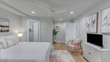 A bedroom with a bed, a chair, a TV, and artwork on the walls.
