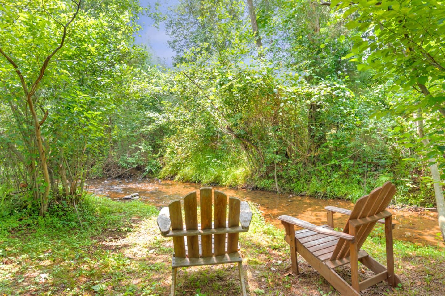 A natural setting with a wooden bench and a small stream.