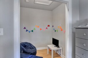 A room with a bed, a desk with a computer, a dresser, and colorful triangular decorations on the wall.