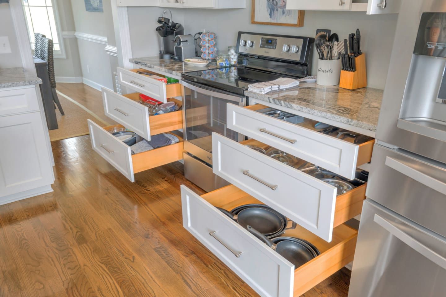 A modern kitchen with white cabinetry, stainless steel appliances, and a marble countertop.