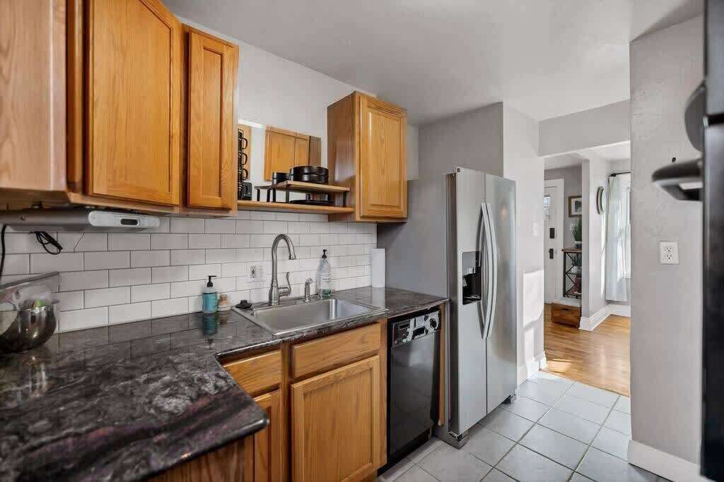 Een moderne keuken met houten kastjes, een roestvrijstalen koelkast en een granieten werkblad.