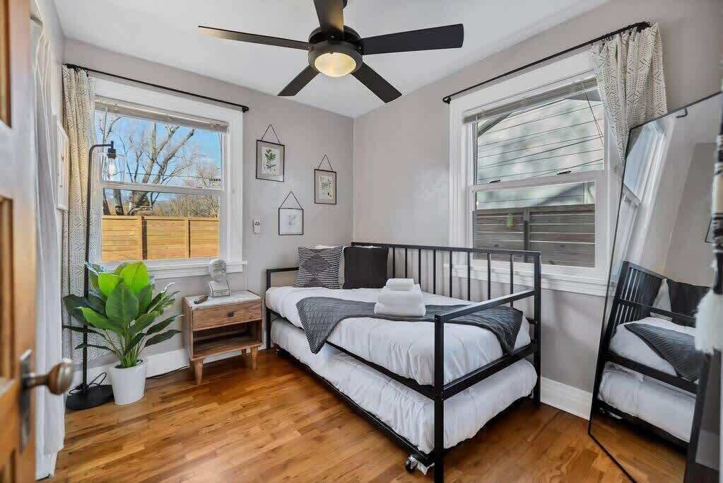 Une chambre à coucher comprenant un lit, un bureau, une chaise, un ventilateur de plafond et une fenêtre.