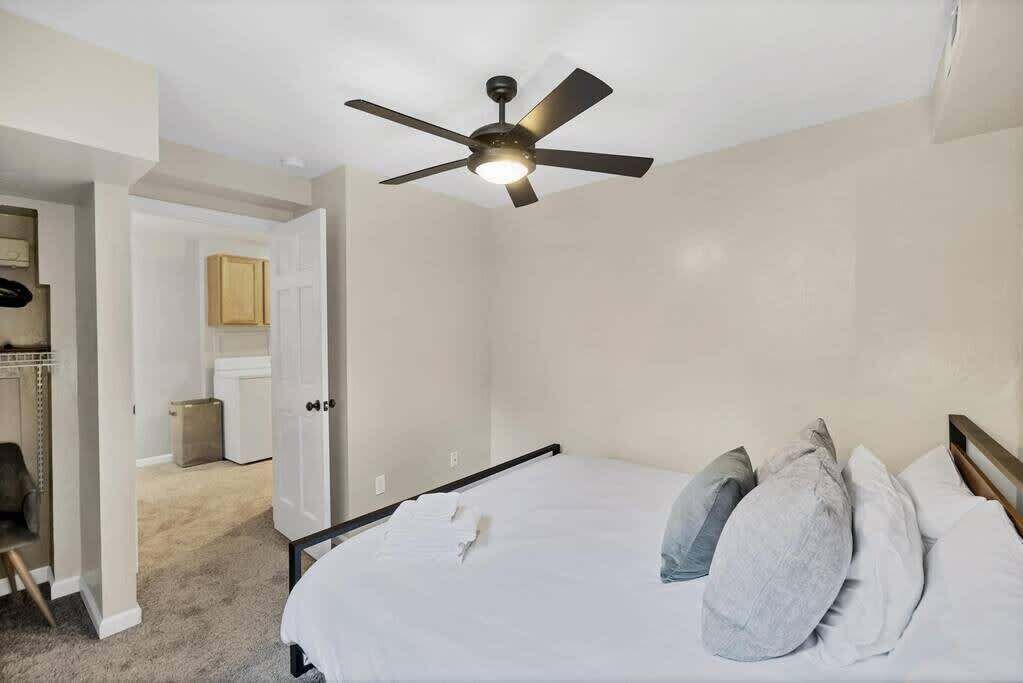 A bedroom with a bed, pillows, a ceiling fan, and a closet.