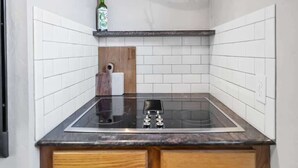 A kitchen with white subway tiles, a black countertop, and wooden cabinetry. - Casa Mosaic! Downtown w BBQ & Workspace! (Colorado Springs)