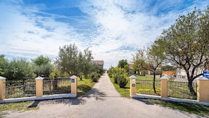 A paved pathway leading to a gated entrance with a clear sky above.