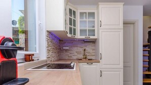 Une cuisine moderne avec des armoires blanches, un pare-feu en pierre et un évier encastré.