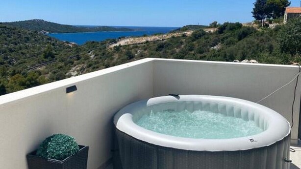 Un jacuzzi sur un balcon offrant une vue sur un paysage côtier.