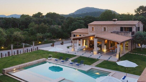 Une maison à deux étages dotée d’une piscine, d’un espace extérieur aménagé et offrant une vue sur le paysage environnant.