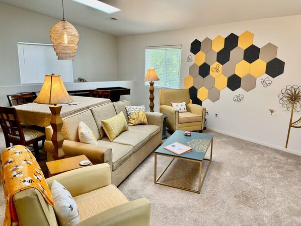 A living room with a sofa, armchairs, a coffee table, and a wall with hexagonal patterns.
