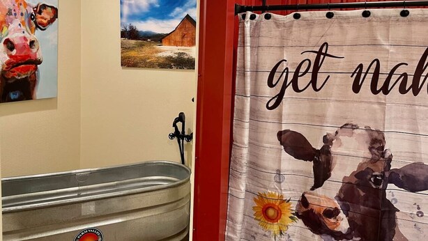 A bathroom with a rustic design, featuring a large bathtub, a shower, and a towel rack.