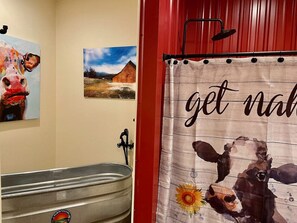 A bathroom with a rustic design, featuring a large bathtub, a shower, and a towel rack.