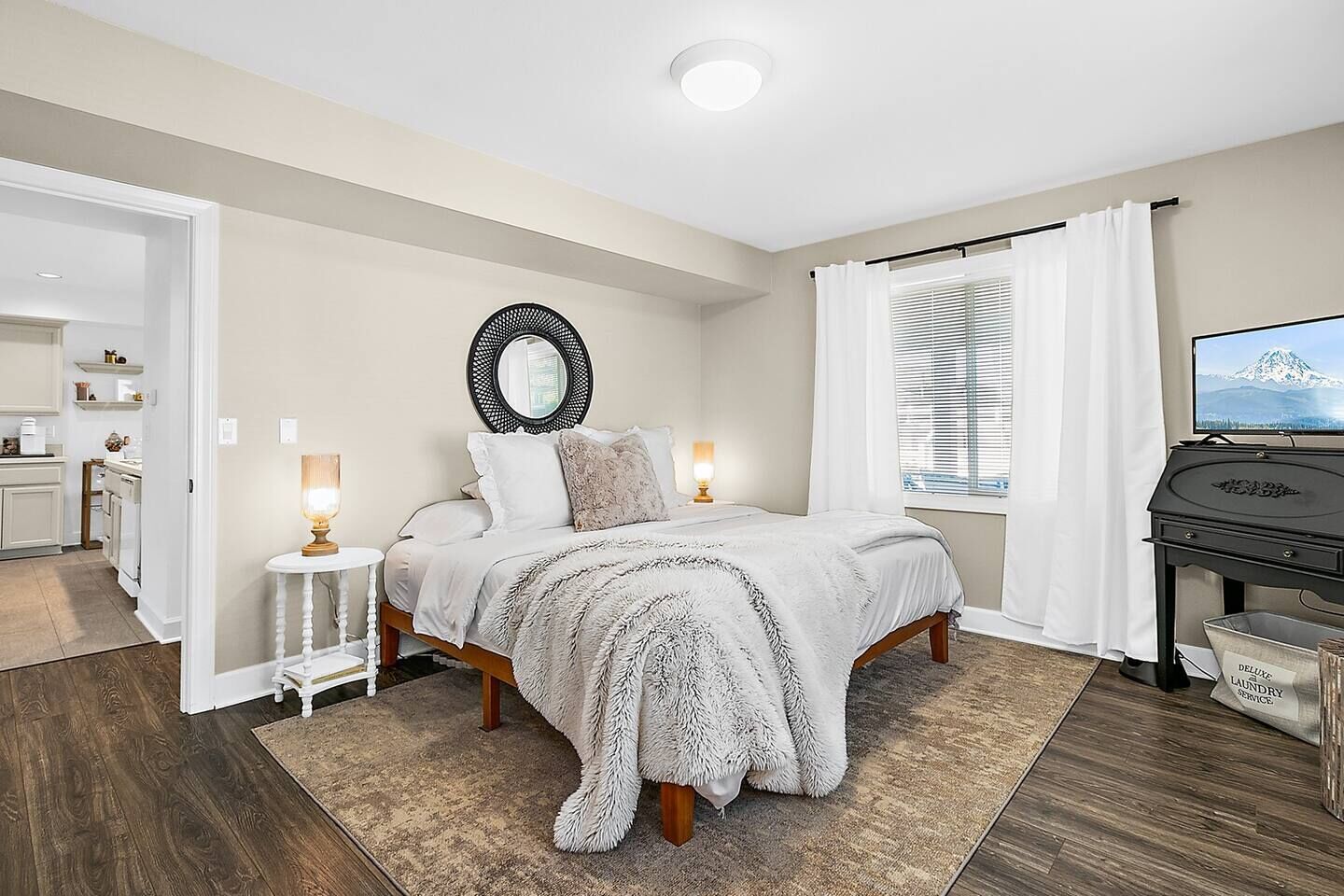 Un dormitorio con cama, lámparas de noche, televisión y señal de servicio de lavandería.