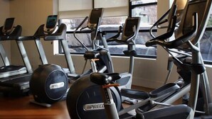 Kuntosalissa on useita kuntoilulaitteita, kuten juoksumattoja ja crosstrainer, ja ikkunasta avautuu näkymä ulos.
