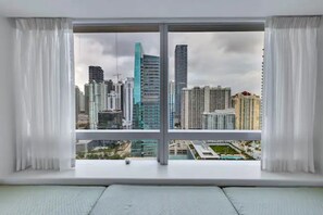 Ein Zimmer mit großem Fenster und Blick auf eine Skyline mit modernen Gebäuden.