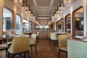 Ein Restaurant mit hohen Decken, Pendelleuchten und einer zentralen Bar.