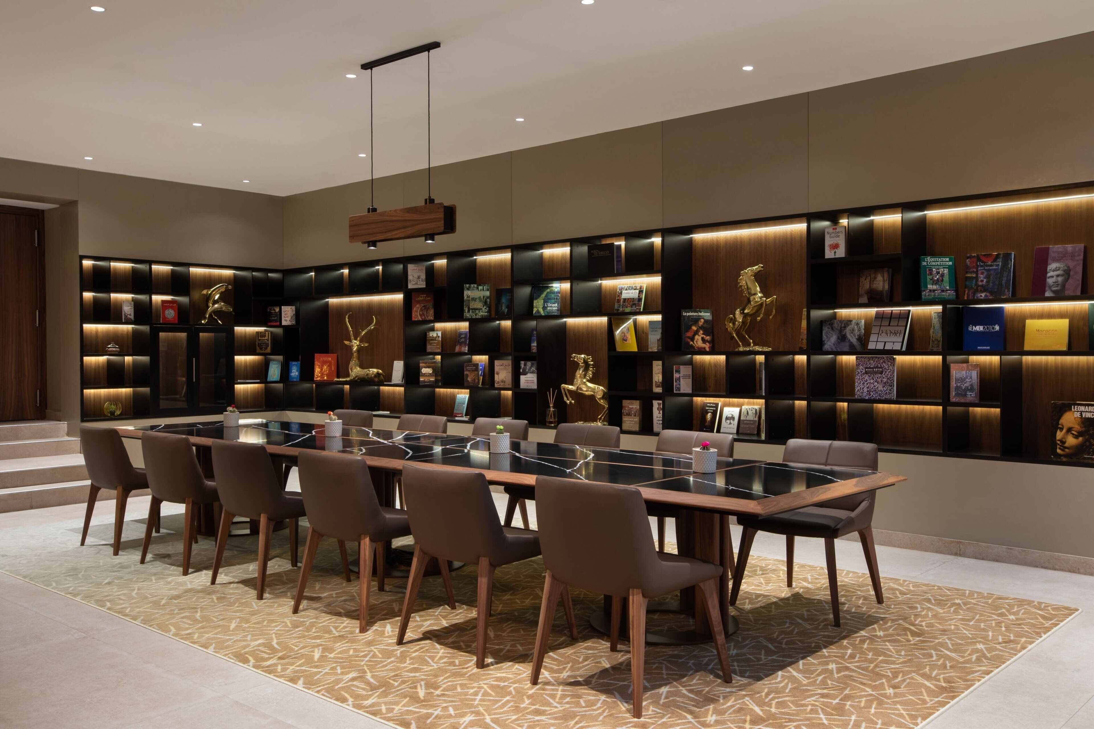 A modern conference room with a glass table, brown chairs, and a wall of framed pictures and awards.