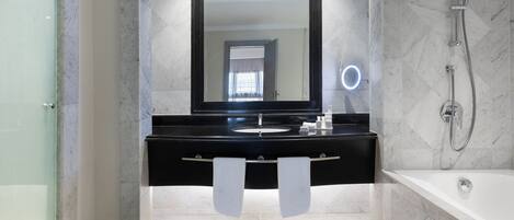 A modern bathroom with a black vanity, a large mirror, a handheld showerhead, and a bathtub.