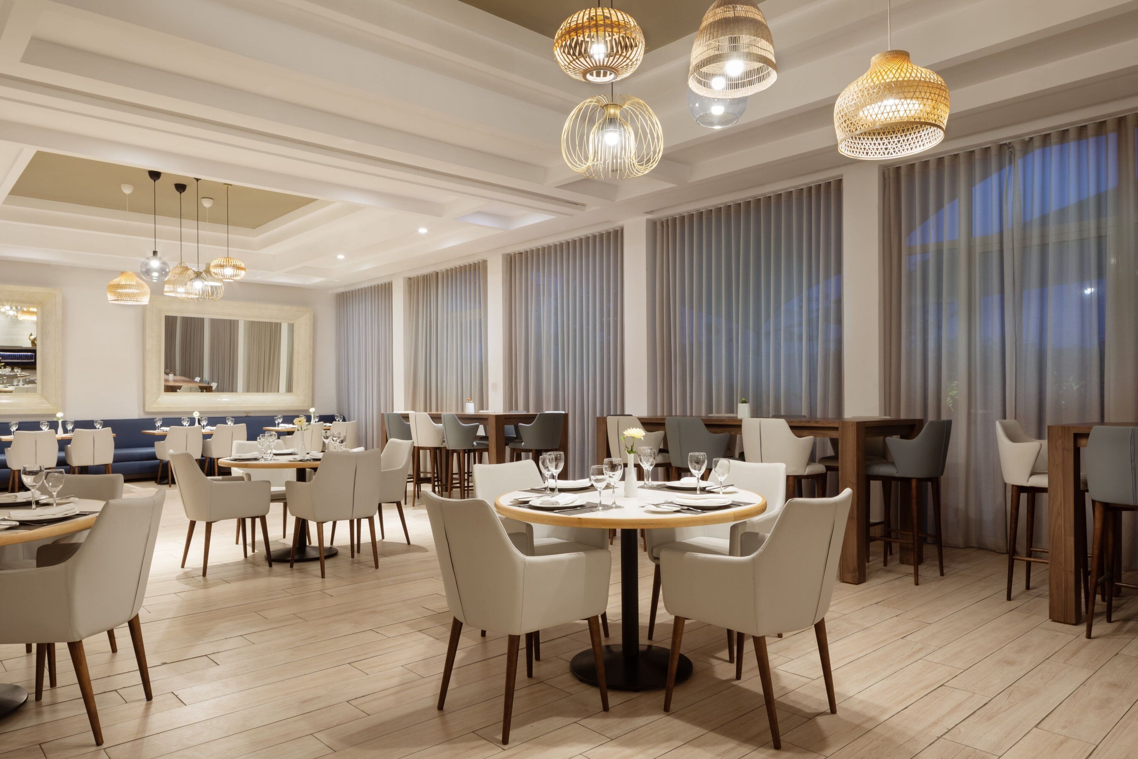 A modern dining area with round tables, chairs, and hanging pendant lights.