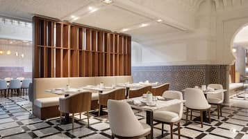 Un restaurante con suelo de cuadros, separadores de madera y asientos tapizados en blanco.